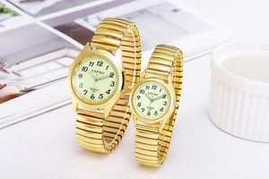 Close-up of golden couple watches with stretch metal bands and luminous dials in a lifestyle setting