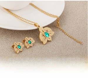 Macro detail of gold flower jewelry set with green cubic zirconia and hollow design
