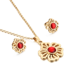 Golden flower jewelry set with red zircon necklace and earrings on white background