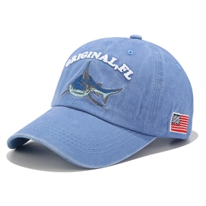 Detail of light blue denim baseball cap with shark embroidery and American flag tag