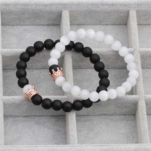 Close-up of black and white crown beaded couple bracelets on a velvet jewelry tray