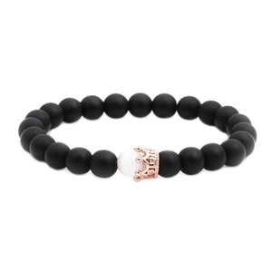 Detail of matte black beads and rose gold crown charm on a stretch bracelet