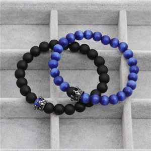 Close-up of blue cat eye and black frosted stone crown bracelets on a display tray
