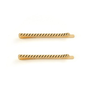 Paire de pinces à cheveux vintage en métal doré avec texture ondulée sur fond blanc