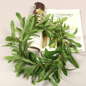 Detailed view of the realistic olive leaf and eucalyptus berry wreath on a minimalist desk