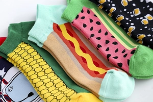 Detail macro view of stacked cotton ankle socks featuring colorful food pattern prints