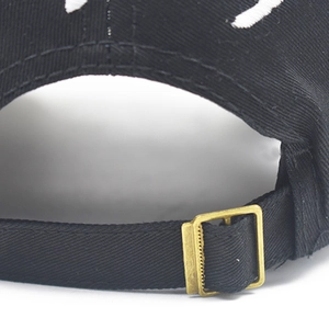 Adjustable bronze metal buckle on a black distressed cotton baseball cap with embroidery