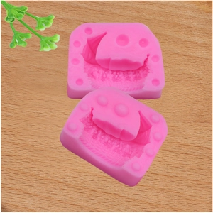 Detailed view of pink silicone baking molds on light wood surface with green accents