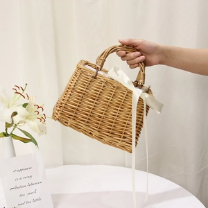 Detail of handmade woven straw bag with white ribbon bow decoration for summer beach
