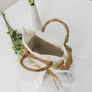 Detail of hand-woven square straw bag with white silk bow and drawstring lining
