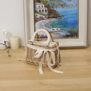 Detail of hand-woven wicker bag with white lace bow on a rustic wooden table