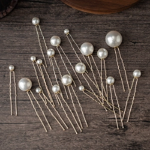 Macro detail of various sized pearls on gold U-shaped bridal hair pins on wood background