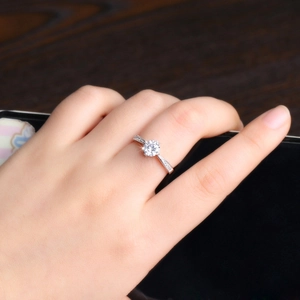 Close-up of a silver ring with a round zircon center stone and diamond side accents