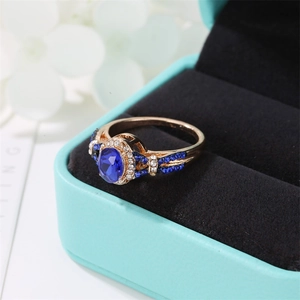 Macro detail of a gold ring with an oval blue sapphire and pavé-set diamonds on velvet