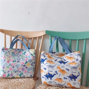 Details von Baumwoll-Lunchtaschen mit Blumen- und Dinoprint und blauen Tragegriffen