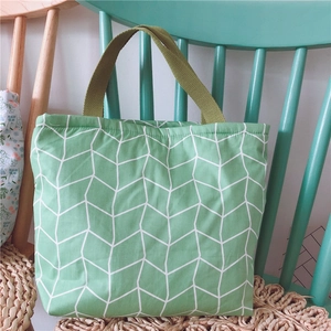 Detail der grünen Canvas-Tasche mit weißen geometrischen Mustern auf einem hellgrünen Stuhl