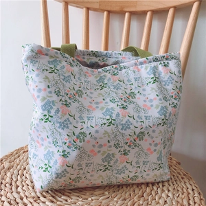 Detail der floralen Canvas-Tragetasche mit grünen Griffen und Vintage-Blumenmustern