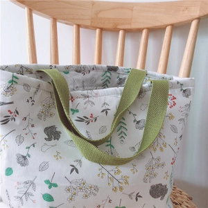 Nahaufnahme einer weißen Stofftasche mit Blumenmotiven auf einem Holzstuhl hängend