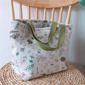 Detail von Blumen- und Eichhörnchenprint auf weißer Canvas-Tasche mit grünen Henkeln
