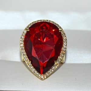 Luxury gold ring featuring a pear-cut red crystal surrounded by clear stones