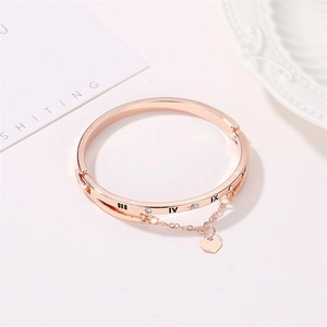 Detail of rose gold bangle with Roman numerals, crystals, and heart charm pendant