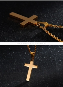 Détail d'un pendentif croix en or poli avec une chaîne en corde sur fond noir élégant