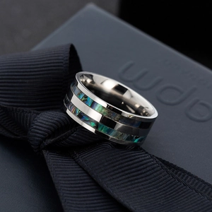 Macro shot of titanium steel ring with double inlaid abalone shell on black ribbon