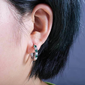 Detail view of silver ear cuff with alternating green and white zircon stones on model