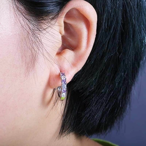 Close-up of a silver ear hoop with alternating purple and white zircon stones on a model