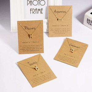 Close-up of four gold zodiac symbol necklaces presented on kraft paper gift cards