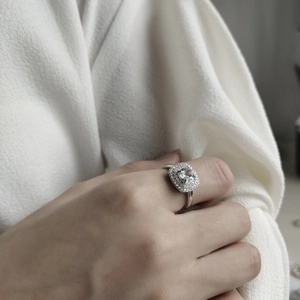 Macro view of a square halo engagement ring with pavé diamonds on a sterling silver band