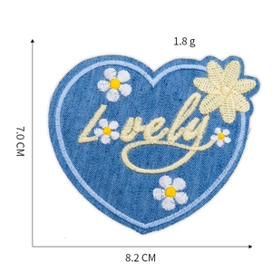 Detail view of heart-shaped denim patch with Lovely embroidery and dimension markings