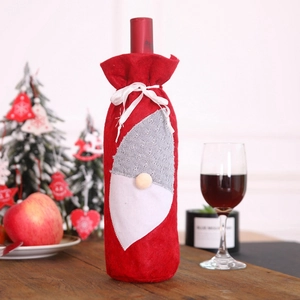 Christmas gnome wine bottle cover in red felt on a festive decorated wooden table