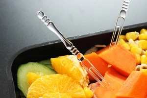 Close-up of clear plastic fruit forks with double prongs and beaded handle detail