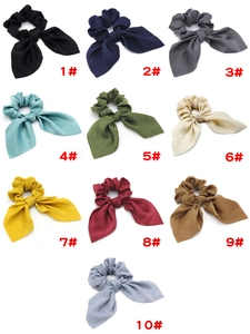 Detail showing ten colorful rabbit ear scrunchies in smooth satin fabric texture