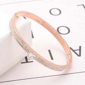 Rose gold titanium bangle with pavé crystals and a central round stone in 45-degree view