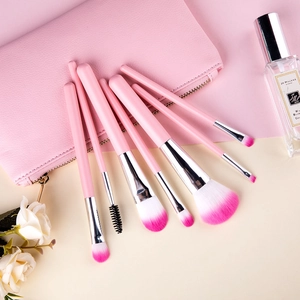 Set of 7 pink makeup brushes with gradient soft bristles and matte handles on floral backdrop