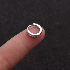 Macro shot of a silver mini hoop earring with clear cubic zirconia on a fingertip