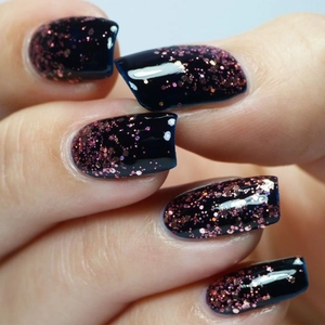 Macro shot of high-shine pink holographic glitter nail polish on dark blue base