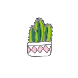 Detailed close-up of a green cactus enamel pin with a pink patterned white flower pot