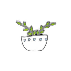 Macro detail of enamel cactus pin featuring white pot with blue dots and green leaves