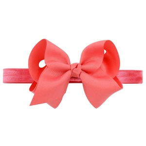 Detailed view of handmade coral pink grosgrain ribbon bow on an elastic baby headband