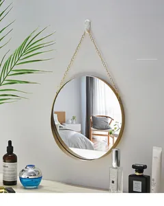 Detail of round gold metal frame wall mirror with hanging chain for modern bathroom decor