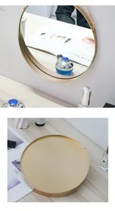 Detail of round wall mirror with golden metal frame and hanging chain for bathroom