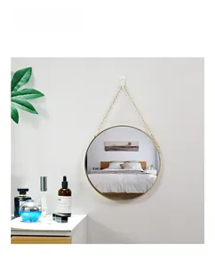 Detail showing the elegant golden metal frame and hanging chain of the round mirror