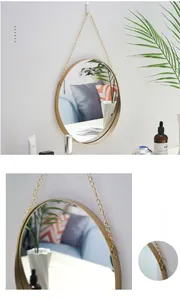 Detail of a round gold metal mirror with a stylish hanging chain for home decor