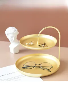 Makro-Detail des nordischen zweistufigen matten Goldmetall-Schmucktabletts mit gebogenem Griff