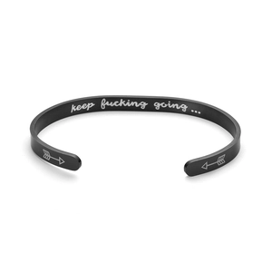 Close-up of black titanium steel cuff bracelet with keep fucking going engraving