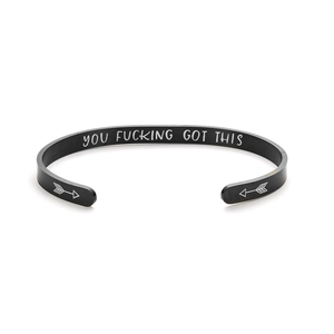 Detail of engraved inspirational quote on matte black stainless steel cuff bracelet