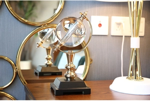 Detailed view of a crystal globe ornament with a gold metal stand on a dark wooden table